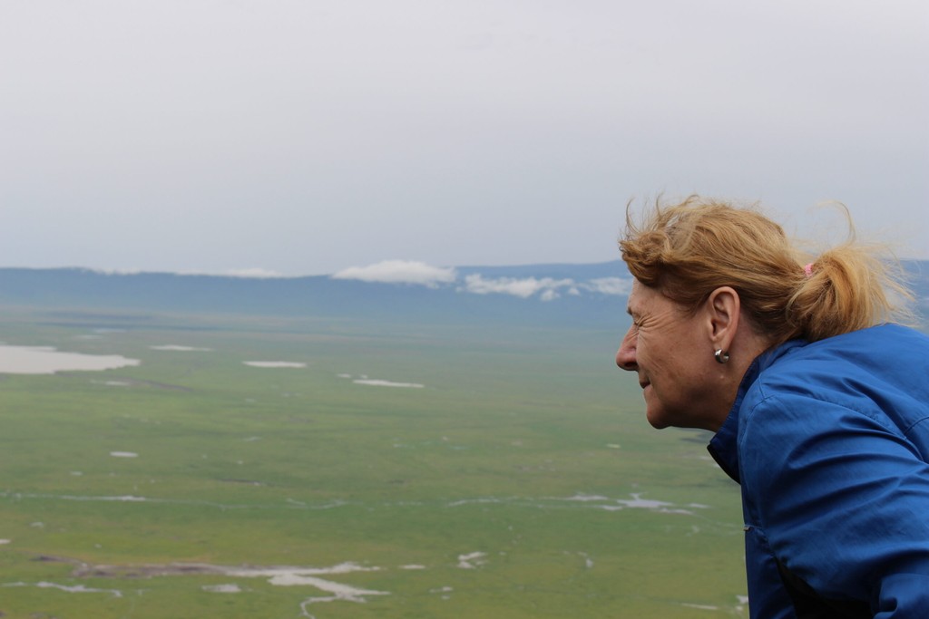 Sie sehen eine blinde Frau, auf einer Aussichtsplattform beim Ngorongoro Crater in Tansania den Kopf nach vorne beugt und die Ohren spitzt. Der Wind fährt durch Ihre Haare. Die Frau war Teilnehmerin der Tansania Reise 2020.